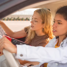 two females on a road trip, one driving and the other reading a map