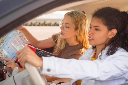 two females on a road trip, one driving and the other reading a map