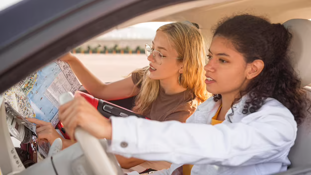 two females on a road trip, one driving and the other reading a map