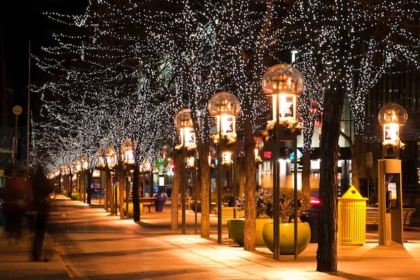 An illuminated street adorned with Christmas lights during the night