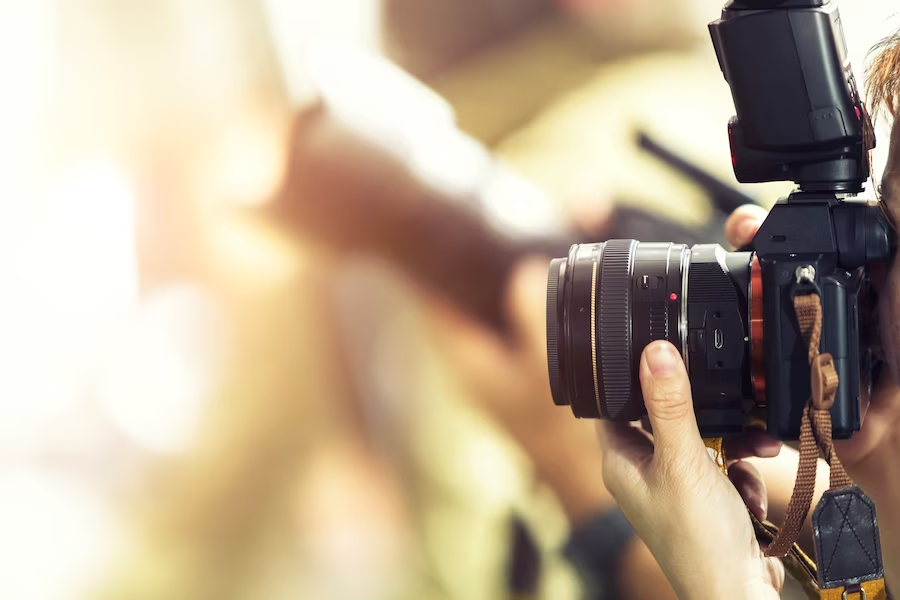 Person with a camera by their face, capturing something in a blurry background