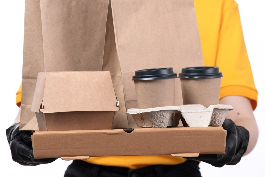 Person wearing gloves holding a tray of food and drinks