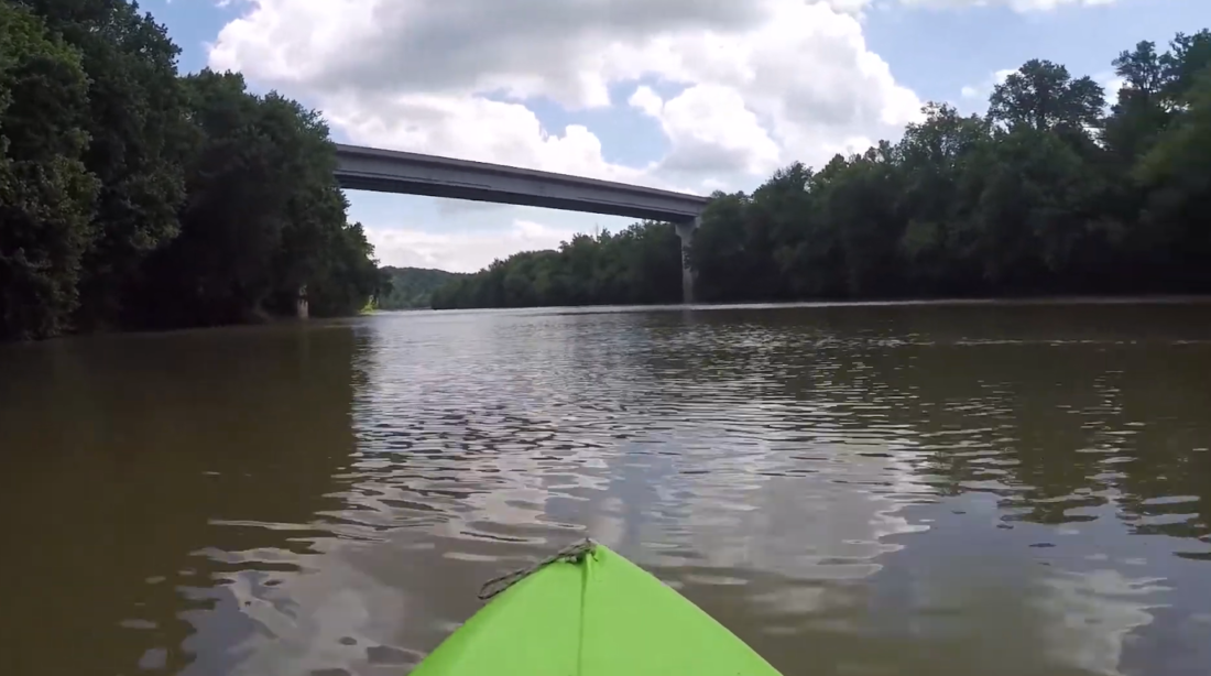 a piece of yellow boat on the river and trees on both sides