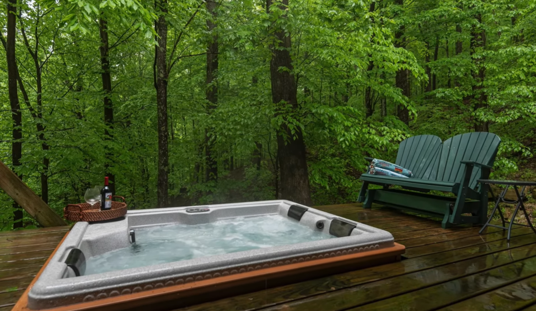a wooden green bench and a jacuzzi in the forest